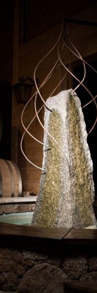 photo d'un menhir sur lequel coule de l'eau via des fils de cuivre