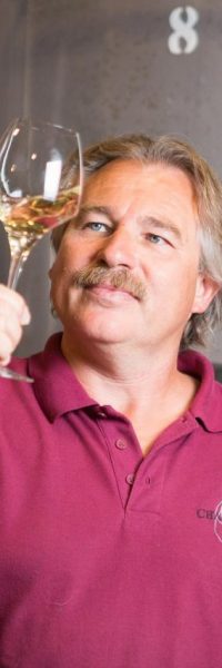 homme qui déguste du vin devant des cuves en inox