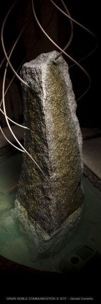 photo d'un menhir entouré d'eau et de 7 fils en cuivre