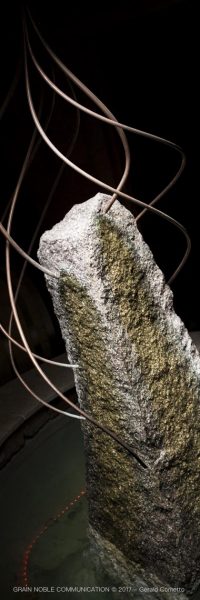 photo d'un menhir entouré d'eau et de 7 fils en cuivre